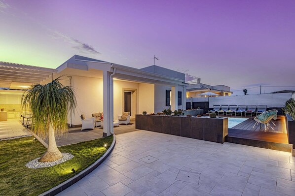 A modern house with a pool, outdoor seating, and a well-maintained garden.