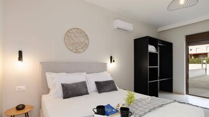 A bedroom with a bed, bedside tables, a wardrobe, and a view of the outside. - Villa Pandora Lindos by Villa Plus (Rhodes)