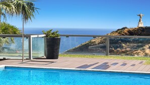 Ein Swimmingpool mit freiem Blick auf den Ozean und einer Statue im Hintergrund.