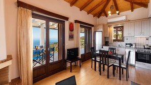A spacious living area with a wooden ceiling and large sliding glass doors leading to a balcony with a view. - Villa Drimonas Erato by Villa Plus (Lefkada)
