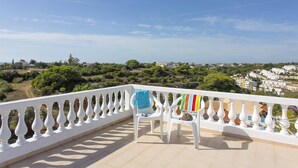 A balcony with white balustrades, two white chairs, and a view of a coastal town. - Villa Curva do Monte by Villa Plus (Praia do Carvoeiro)