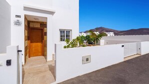A white building with a wooden door, a small window, and a sign reading 'Villa Naya.' - Villa Naya by Villa Plus (Playa Blanca)