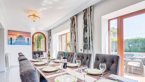 Comedor con una larga mesa dispuesta para seis personas, seis sillas y vistas al exterior.