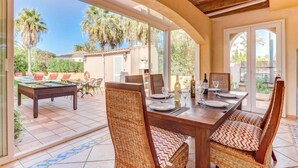 A dining area with a pool table, wicker chairs, and a table set for dining.