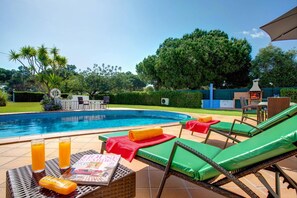 A swimming pool with lounge chairs and a magazine on a table.