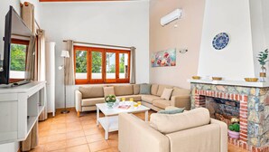 A living room with a sofa, a coffee table, a fireplace, and a television. - Villa Caterina by Villa Plus (Alayor)