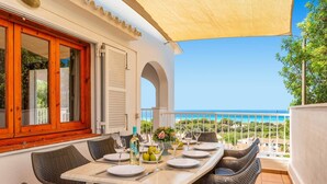 A dining area with a table set for four, overlooking a coastal view. - Villa Caterina by Villa Plus (Alayor)