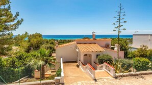A coastal property with a tiled roof, a stone pathway leading to a gate, and a clear view of the sea. - Villa Caterina by Villa Plus (Alayor)