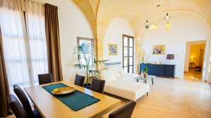 A spacious living area with a dining table, sofa, and a dark-colored cabinet. - Villa Flavia by Villa Plus (San Vito dei Normanni)