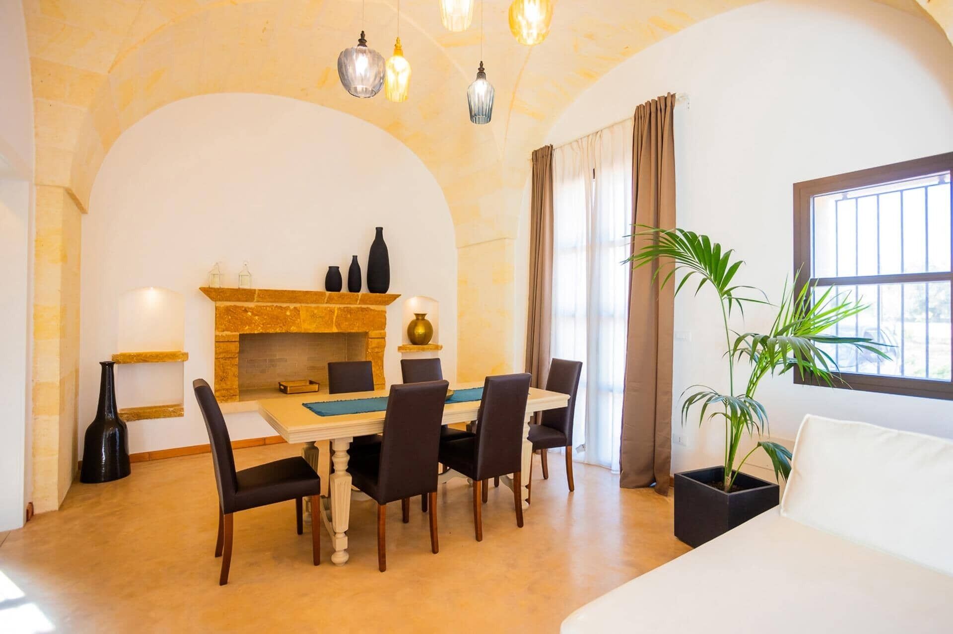 Un comedor con chimenea de piedra, una mesa con sillas y una planta en maceta.