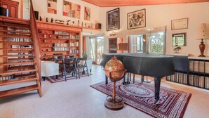 Une pièce spacieuse avec une grande bibliothèque en bois, un piano à queue et un globe terrestre posé sur un socle.