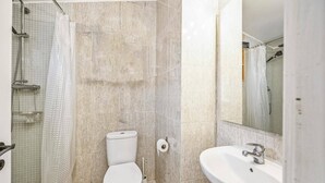 Un baño con inodoro, lavamanos y zona de ducha.