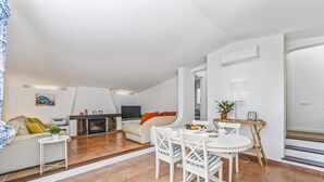 Una sala de estar moderna con chimenea, comedor con mesa y sillas, sofá y televisor.