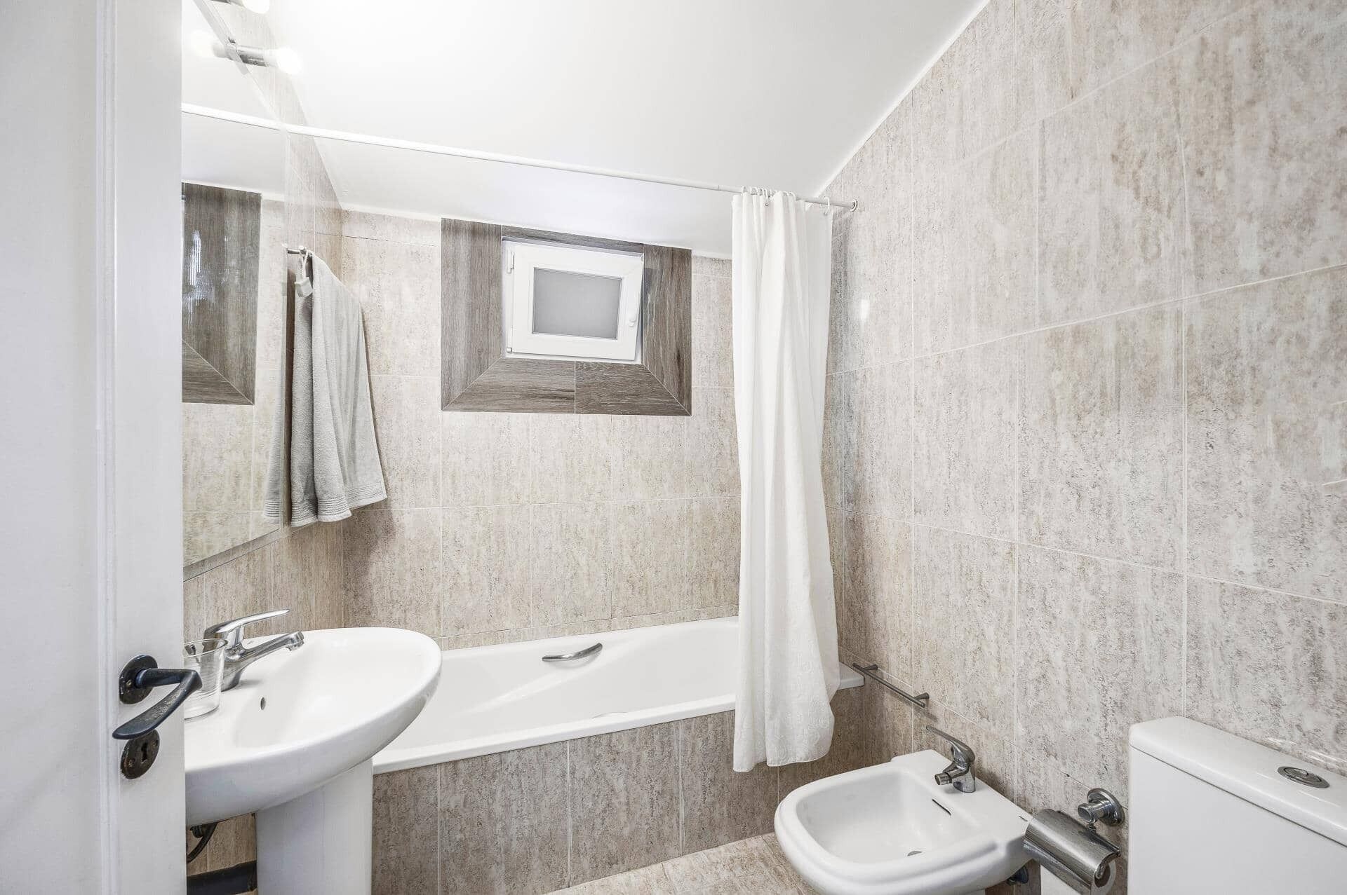 Een badkamer met een bad, een wastafel, een toilet en een bidet.