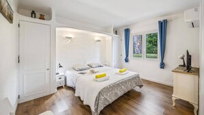 Un dormitorio con cama, mesitas de noche, escritorio y ventana con cortinas.