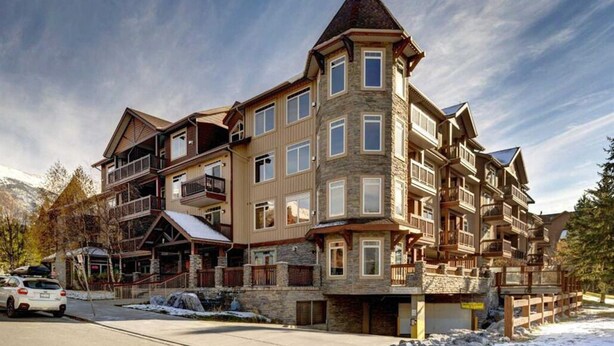 Un hôtel à plusieurs étages, doté d’une façade en pierre, de balcons et d’une entrée aménagée comme un chalet de ski.