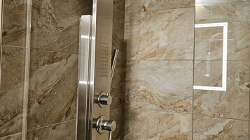 A modern shower enclosure with a curved showerhead and control knobs.