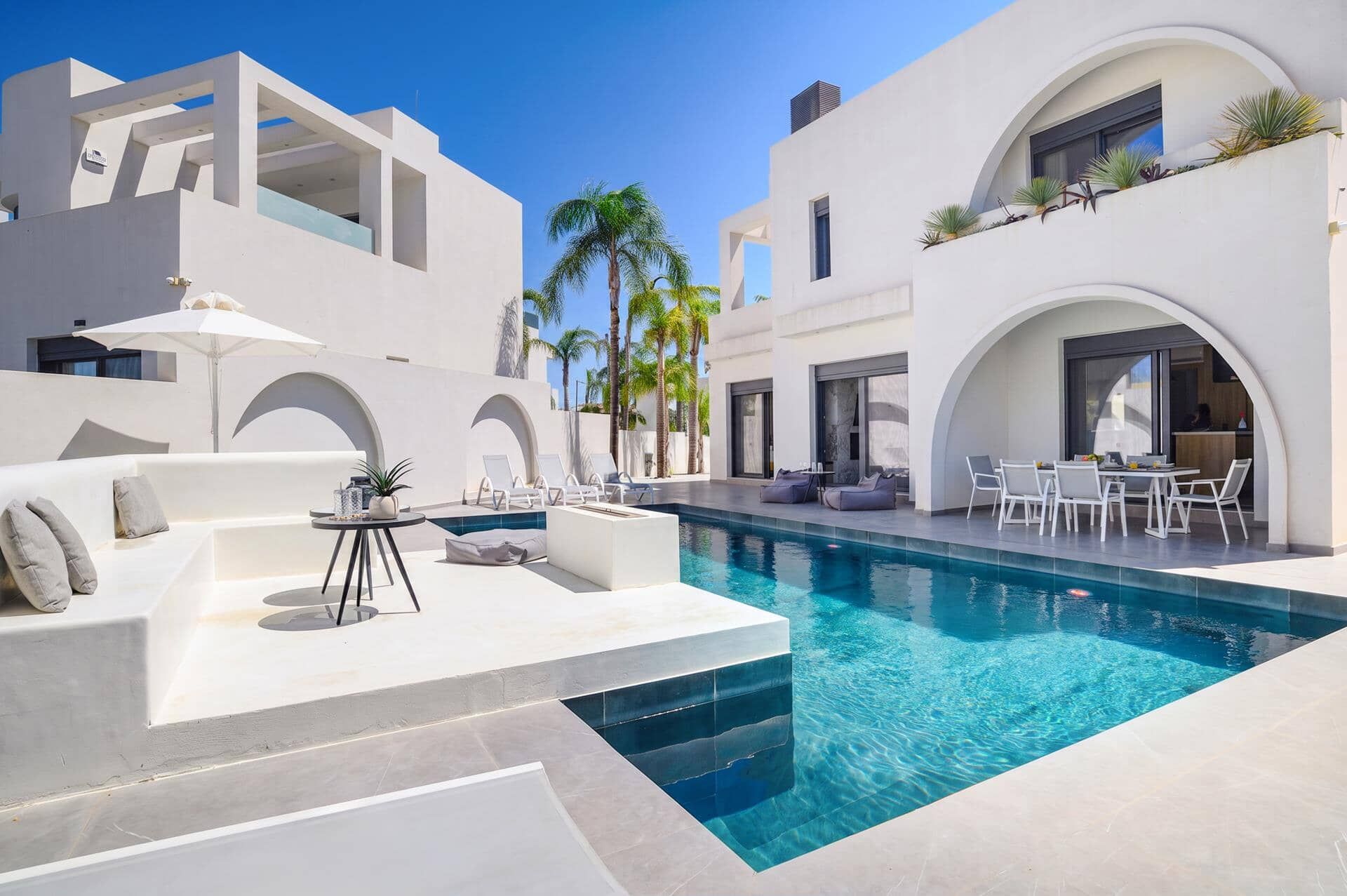 A modern pool area with lounge chairs, a small table, and a pool with clear blue water.