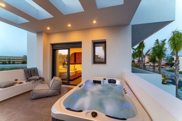 Un balcón moderno con bañera de hidromasaje, zona de estar y vistas al mar.
