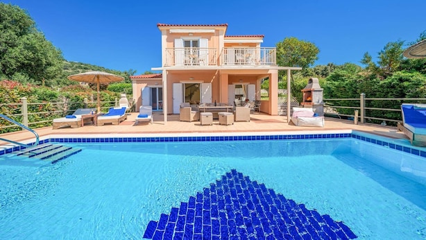 Ein zweigeschossiges Haus mit Swimmingpool, Gartenmöbeln und einer Grillgelegenheit.