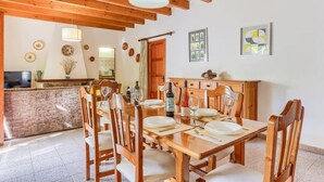 A dining area with wooden furniture, a table set for four, and a wooden ceiling with exposed beams. - Villa Rabasso by Villa Plus (Pollença)