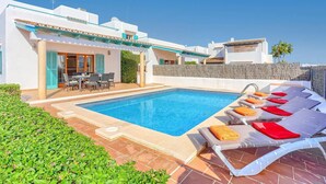 Une piscine avec des chaises longues et un espace patio.