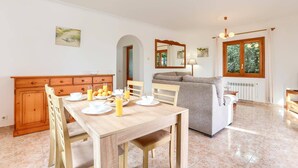 Un coin repas avec une table en bois mise pour le petit-déjeuner, un canapé et un radiateur.