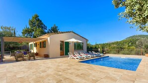 A pool area with lounge chairs, a pergola, and a small building with shutters. - Villa Marinada by Villa Plus (Pollença)