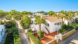 A coastal residential area with white houses, palm trees, and a clear blue sky.