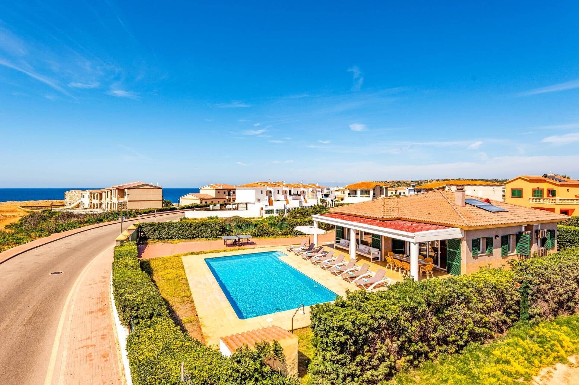 Un resort costero con piscina, sillas de descanso y vistas al mar.
