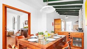 A dining area with a wooden table, leather chairs, and a kitchen in the background. - Villa Casa Bonita by Villa Plus (Alayor)