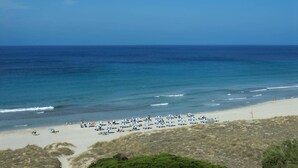 A beach with numerous umbrellas and sun loungers, a sandy shore, and the ocean in the background. - Villa Casa Bonita by Villa Plus (Alayor)