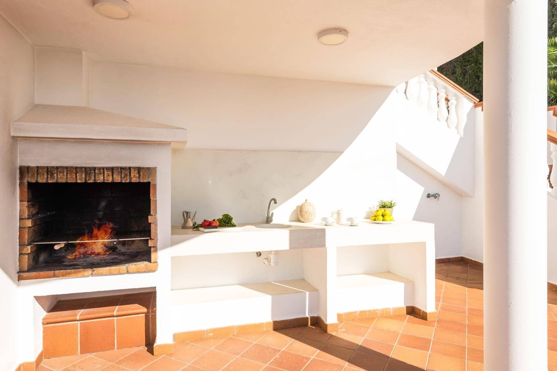 An outdoor kitchen with a brick oven, a sink, and a countertop with various items.