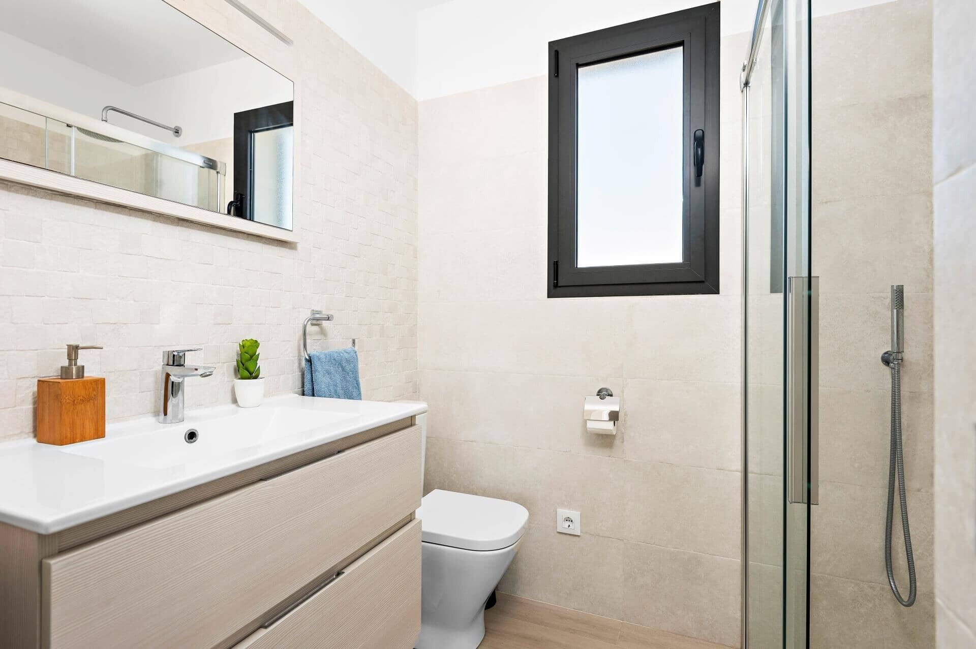 A modern bathroom with a white sink, a toilet, and a glass shower enclosure.