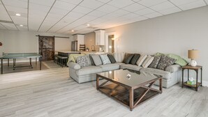 A spacious living room with a sectional sofa, a glass-top coffee table, and a ping pong table. - Lake Hartwell Getaway w/ Private Dock + Fire Pit! (Fair Play)