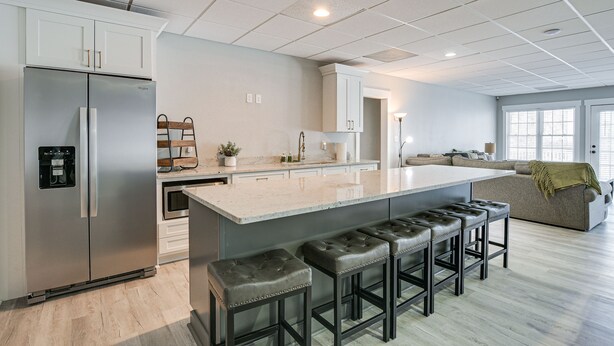 A modern kitchen with a stainless steel refrigerator, a large island with bar stools, and a built-in oven. - Lake Hartwell Getaway w/ Private Dock + Fire Pit! (Fair Play)