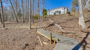 A wooden boardwalk leading to a white house surrounded by trees. - Lake Hartwell Getaway w/ Private Dock + Fire Pit! (Fair Play)