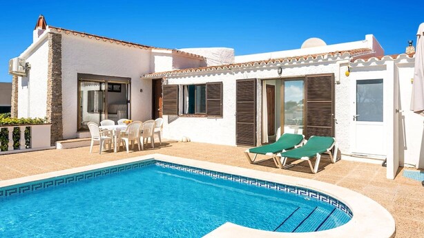 A pool area with a sun terrace, white walls, and a small dining set. - Villa Shambala by Villa Plus (Cala en Porter)