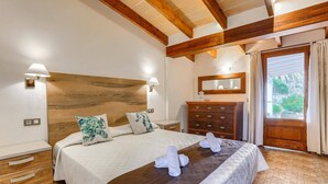 Un dormitorio con cabecera de madera, una cama con ropa blanca, dos lámparas de noche, un aparador y un espejo sobre el aparador.