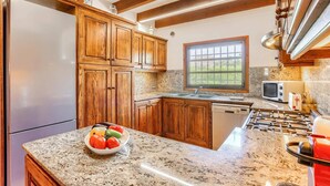 Una cocina con armarios de madera, encimeras de granito, una ventana, un microondas y una estufa a gas.