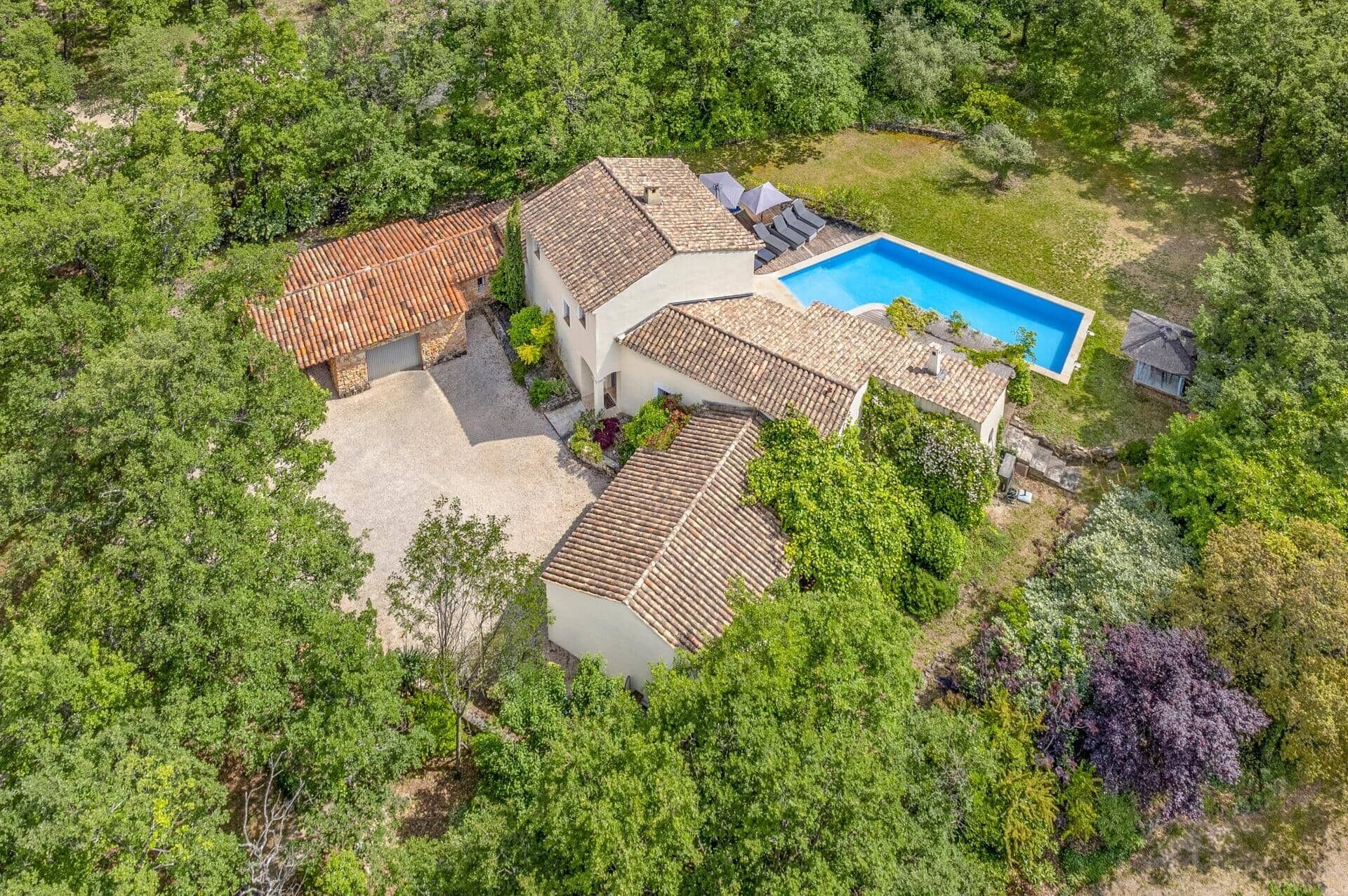 Una villa con piscina rodeada de exuberante vegetación.