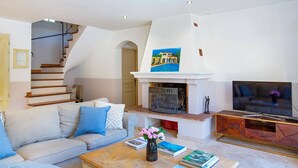 A living room with a sofa, coffee table, books, a fireplace, and a TV. - Villa Beauregard by Villa Plus (Tourrettes)