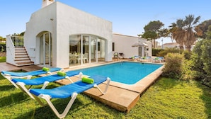 A modern villa with a swimming pool, outdoor seating, and a staircase leading to a covered patio. - Villa Bini Cinco by Villa Plus (Binibeca)