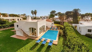 A modern villa with a swimming pool, surrounded by well-maintained gardens and other villas. - Villa Bini Cinco by Villa Plus (Binibeca)