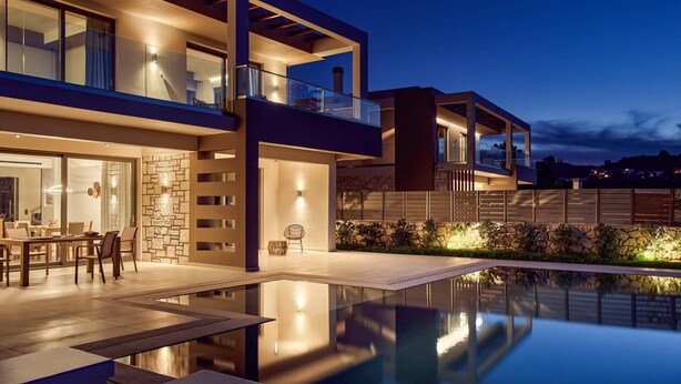 Una moderna casa a due piani con piscina, pareti in pietra e un balcone.