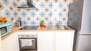 Eine Küche mit gemustertem Fliesenspiegel, einer Edelstahl-Spüle, einer Mikrowelle und einem eingebauten Backofen.