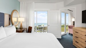 A hotel room with a bed, a desk with a lamp, a chair, a dresser, and a balcony with a table and chairs. - Marriott's SurfWatch (Hilton Head Island)