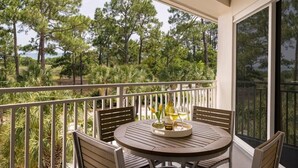 A balcony with a round table, chairs, and a bottle of wine. - Marriott's SurfWatch (Hilton Head Island)