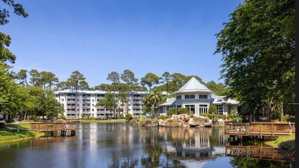 A hotel with a large building and a smaller structure with a dome roof, surrounded by a lake and trees. - Marriott's SurfWatch (Hilton Head Island)