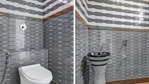 Une salle de bain avec des toilettes blanches, un lavabo moderne et un mur recouvert de carreaux avec un motif à rayures.